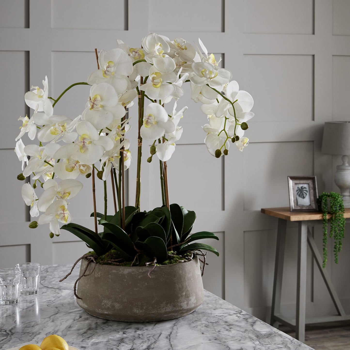 A large faux white Orchid in a stone pot 