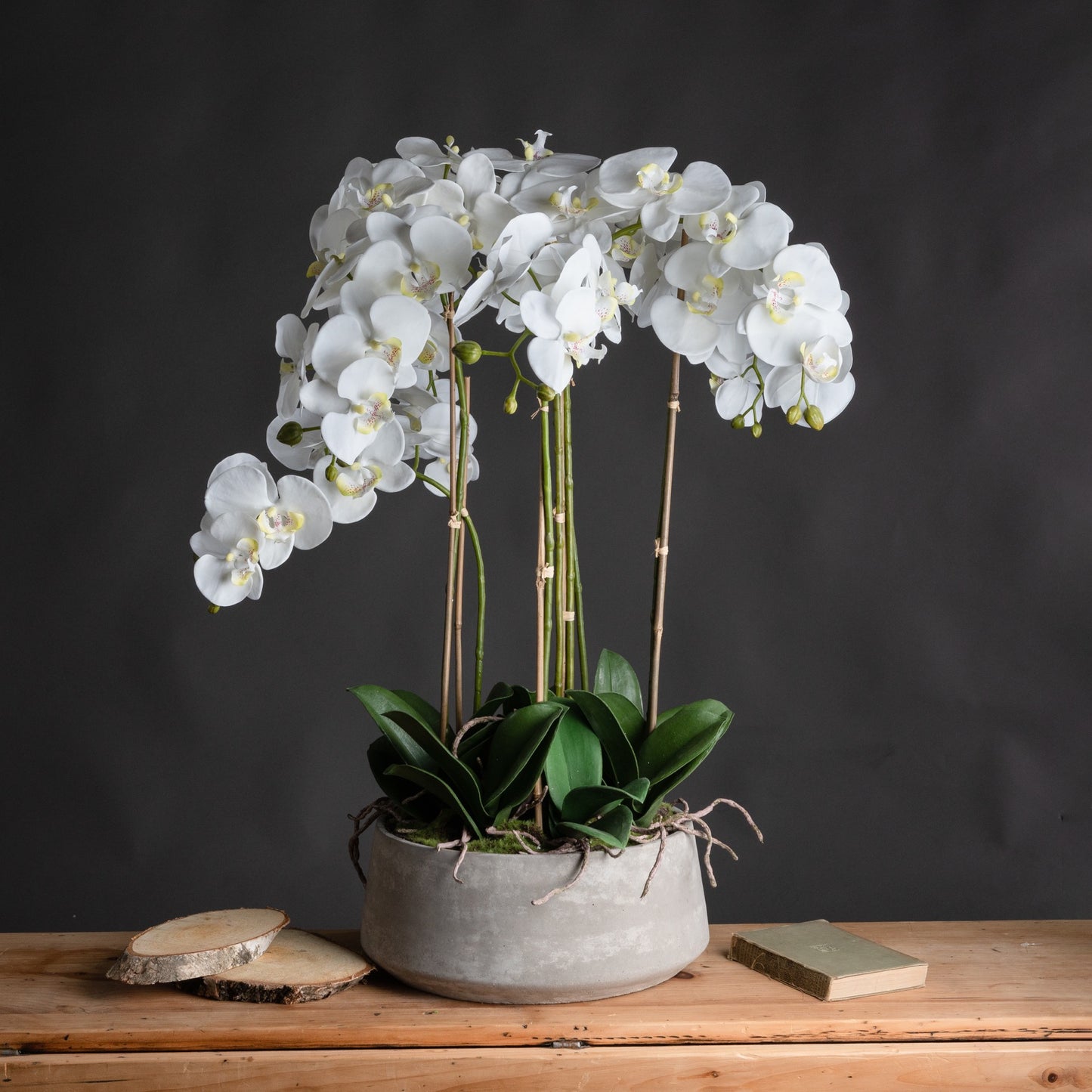 A large faux white Orchid in a stone pot 