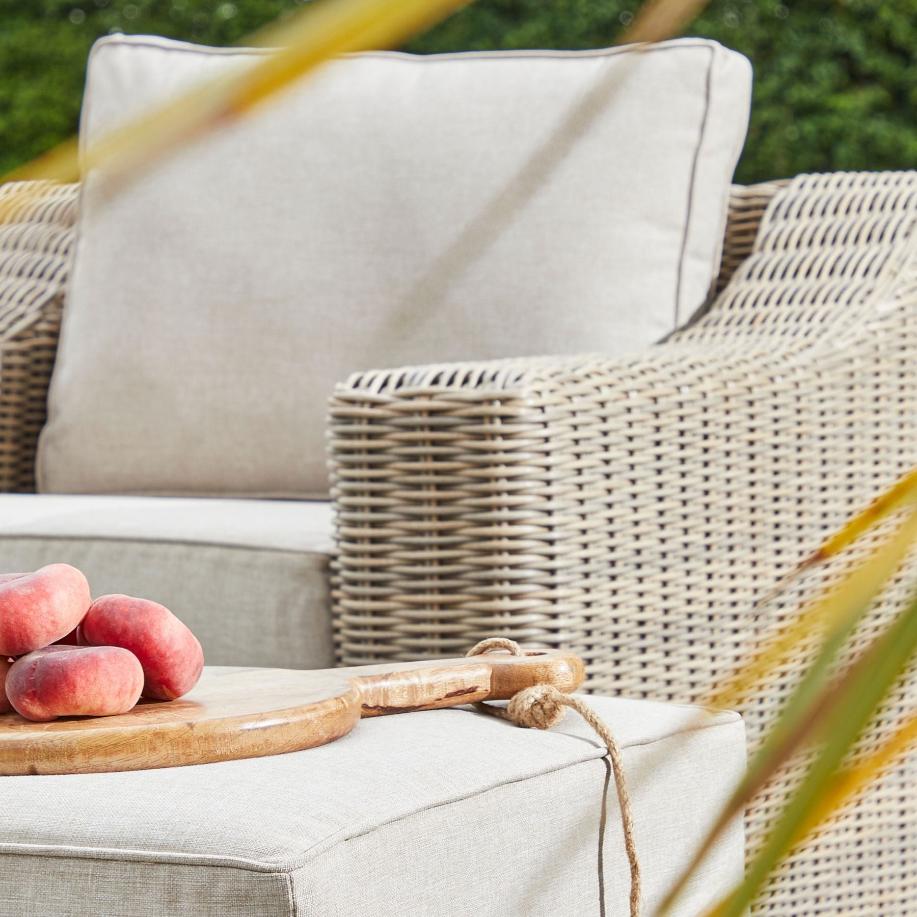 Wicker outdoor armchair with cream cushions