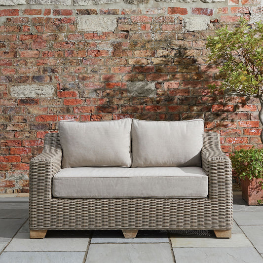 Wicker style outdoor sofa with cream cushions