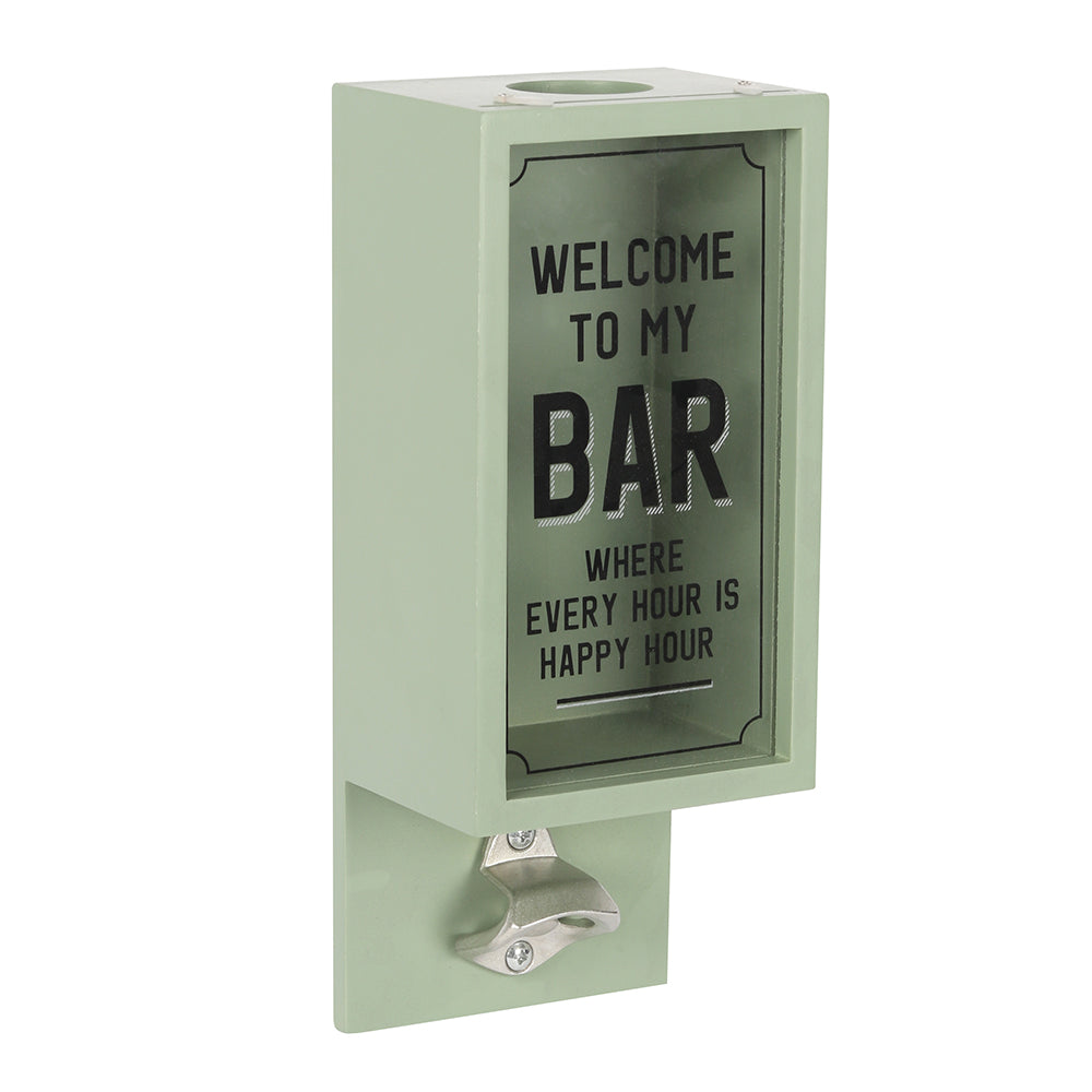 A wall mounted bottle opener with words ‘welcome to my bar’ and a box for collecting lids 