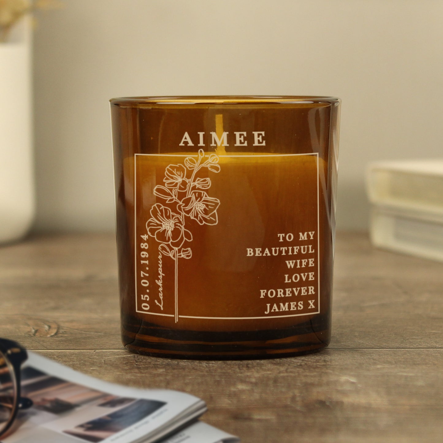 Candle in an amber colour glass container and label with a picture of July’s Birth Flower and space for a personalised name and message 