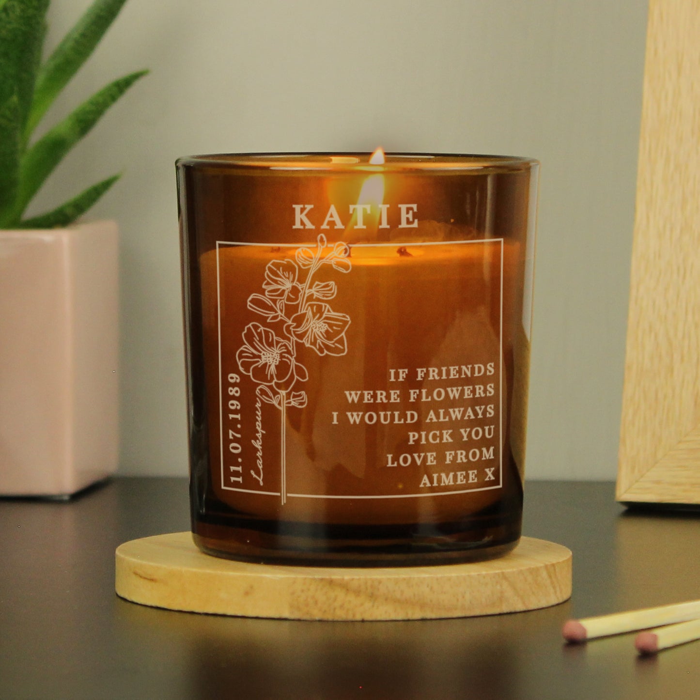 Candle in an amber colour glass container and label with a picture of July’s Birth Flower and space for a personalised name and message 