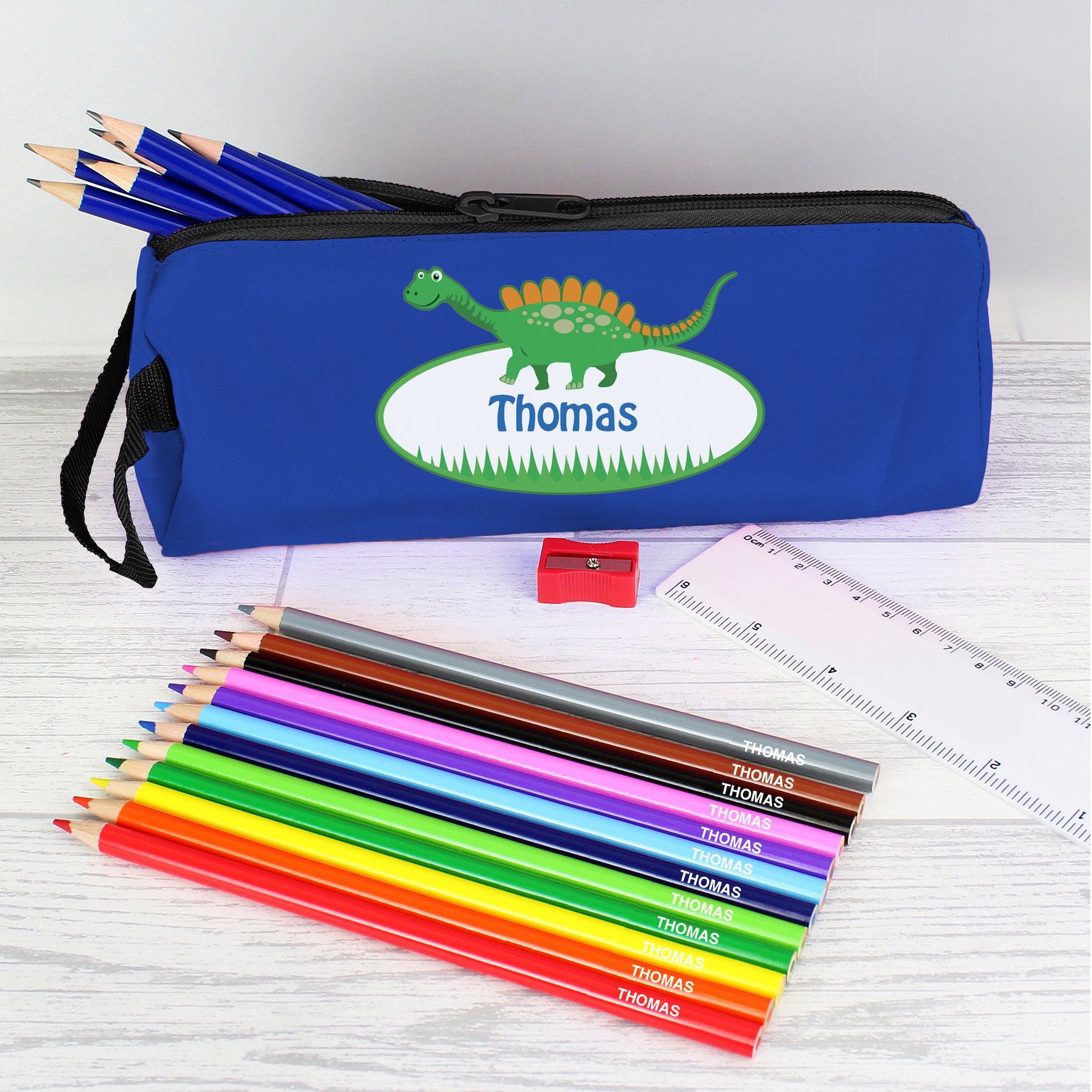 Blue pencil case with picture of dinosaur and personalised with name. Set of coloured pencils personalised with name. 