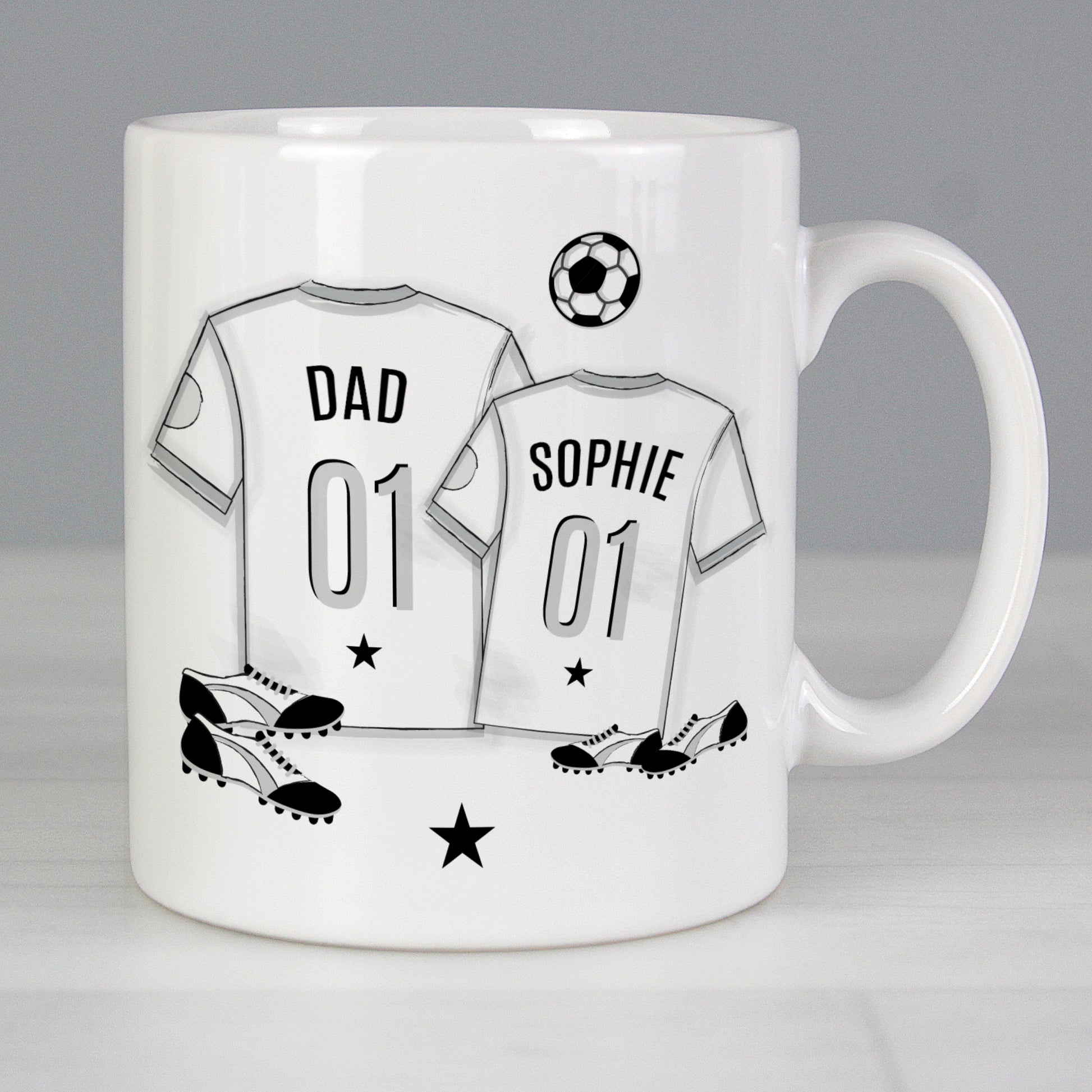 Mug with T-shirt print with personalised name. 1 large T-shirt and 1 small T-shirt with football and football boots in background. 